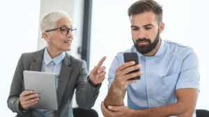 Duas pessoas sentadas lado a lado em conversa, uma orientando a outra